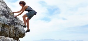 A woman scaling a rockface on a sunny day